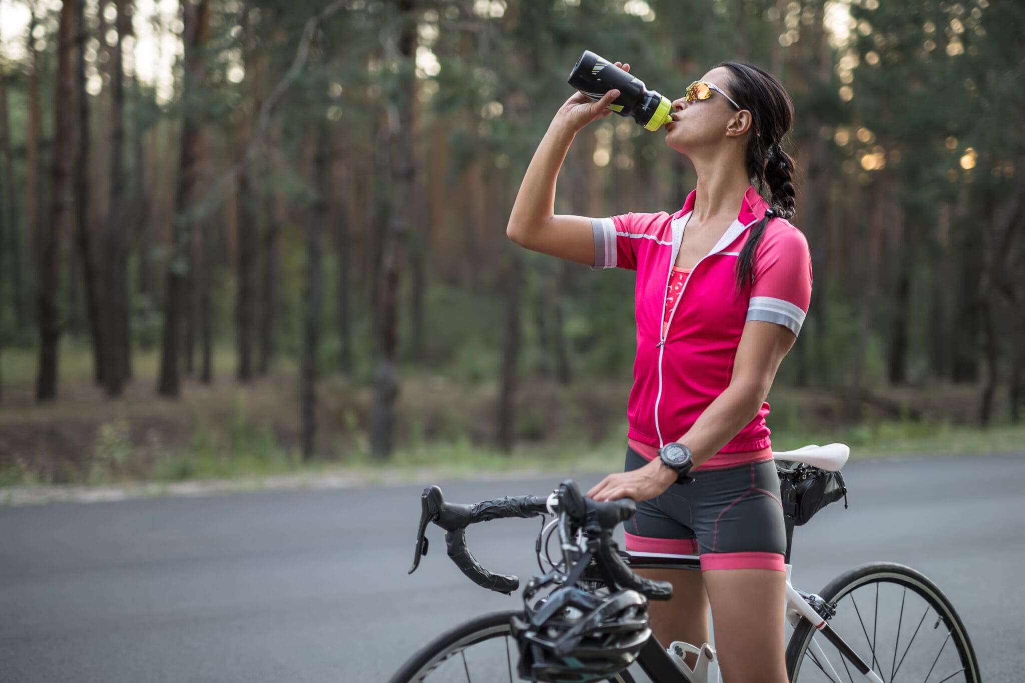 Woman on a sports bicycle drinking a sports drink