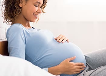 Pregnant woman holding her belly and smiling