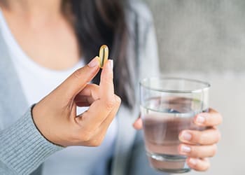 Woman holding a vitamin pill and a glass of water