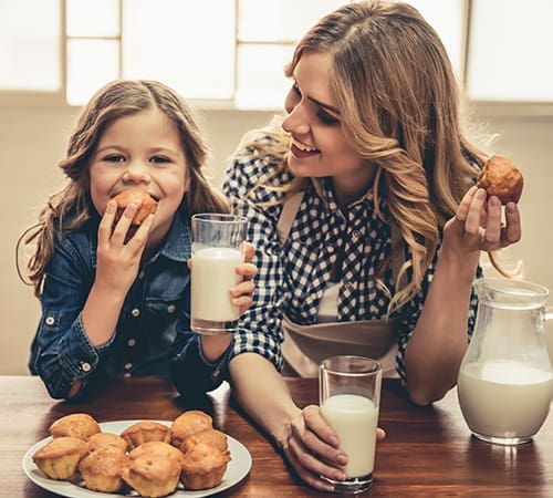 mother and daughter eating cookies and drinking milk